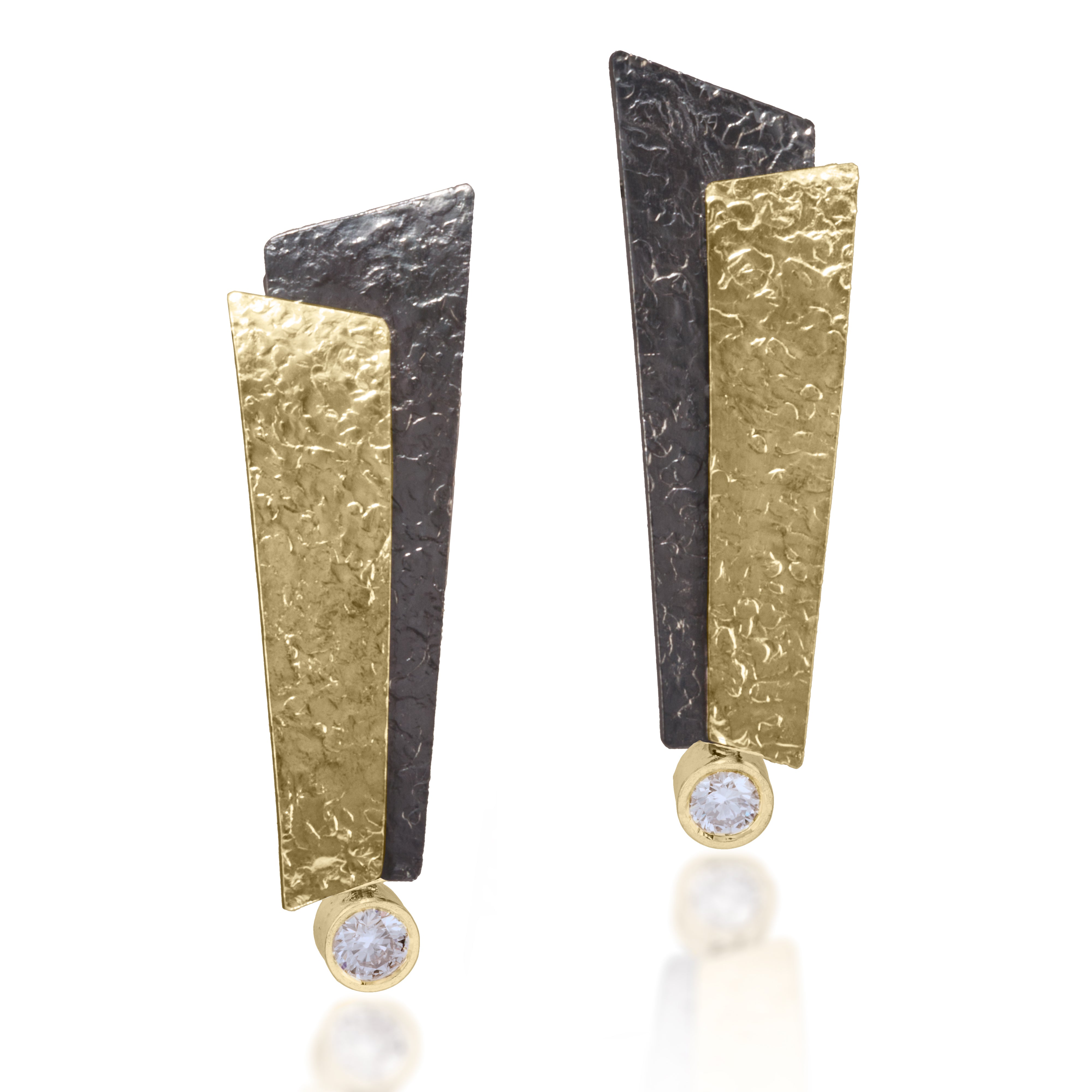 This dramatic earring has been created in 18k bi-metal and oxidized sterling silver accented with various bezel diamonds. Hand fabricated, hammer textured with house fabricated lever backs. tcw. varies by design.