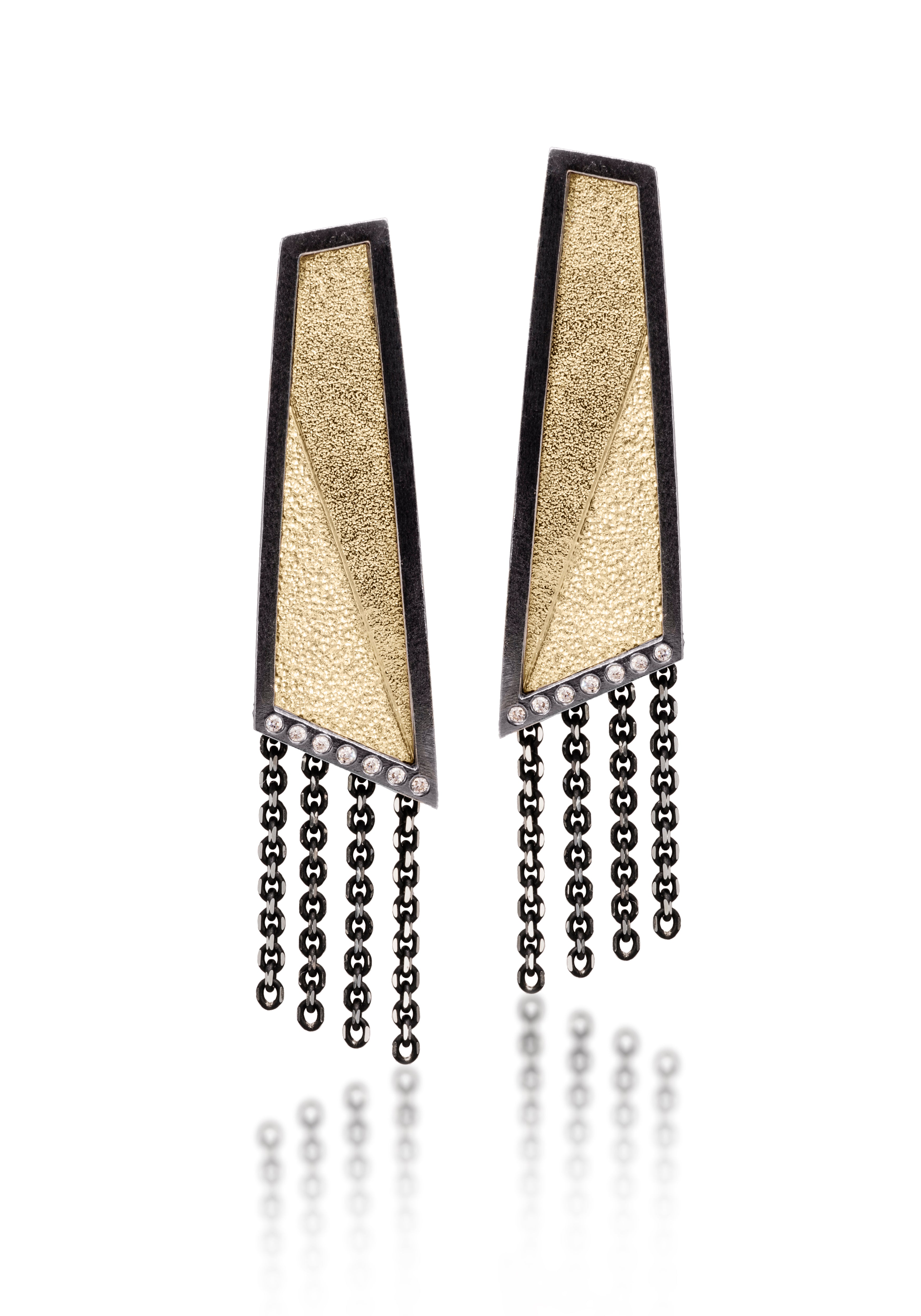 This earring in oxidized sterling silver and richly textured 18k bimetal, is flush set with ideal cut white diamonds. It features 14k gold posts or 18k gold ear wires. Accent facet glitters with the texture of diamond facets, individually scored and textured. Elongated shape, size medium. Available in post, post fringe, drop and drop fringe styles. 0.0966 tcw