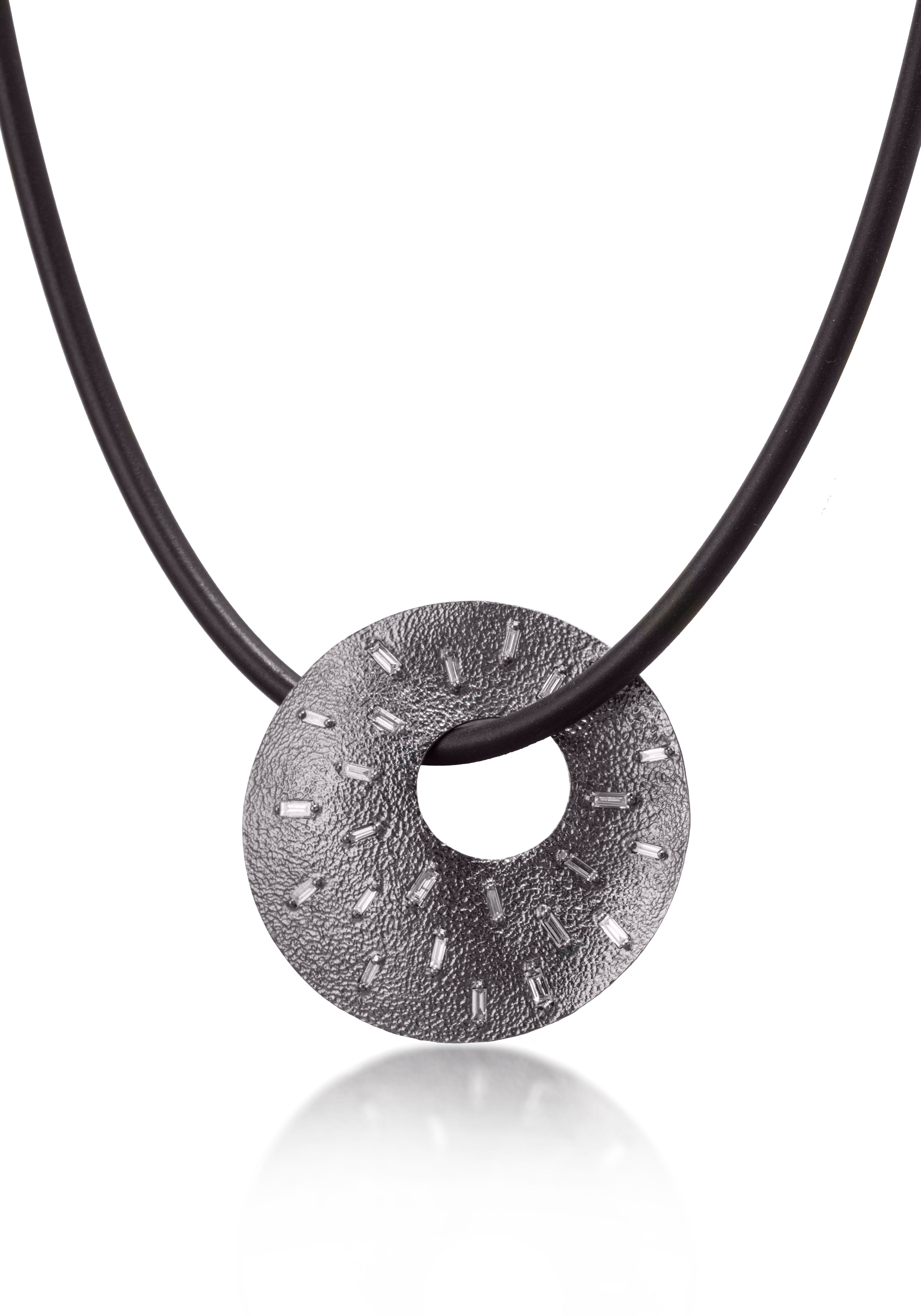 This unique radial pendant makes elegant use of space and line. Featuring 26 white diamond baguettes and richly textured oxidized silver, the necklace comes to life with the slightest bit of light. 0.778 tcw