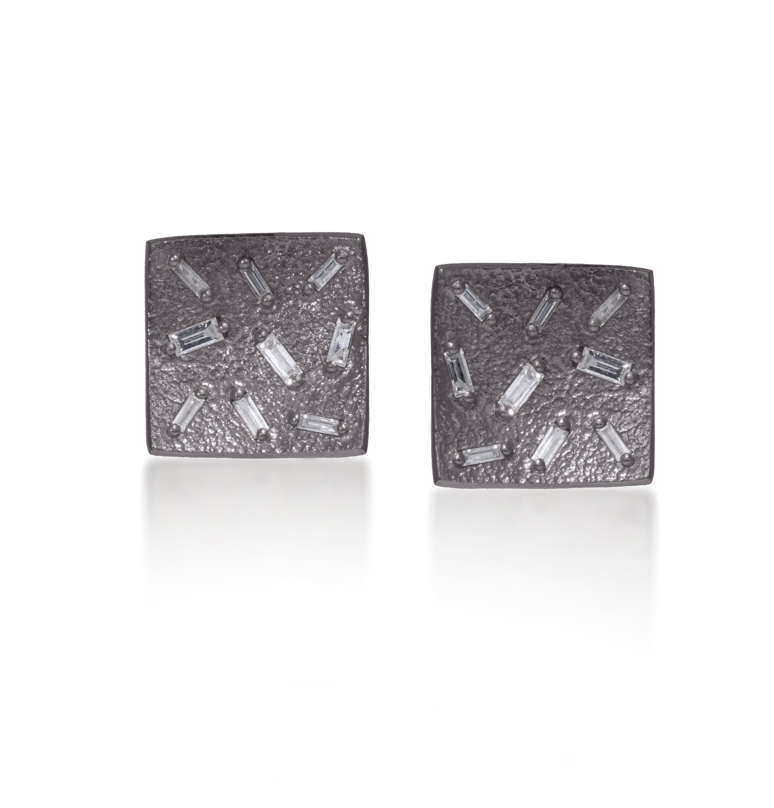 This simple yet elegant post earring is perfect for everyday. Offered in three richly textured color ways, oxidized sterling, 18k gold, palladium. Each earring set with 9 white diamond baguettes. 0.5 tcw.
