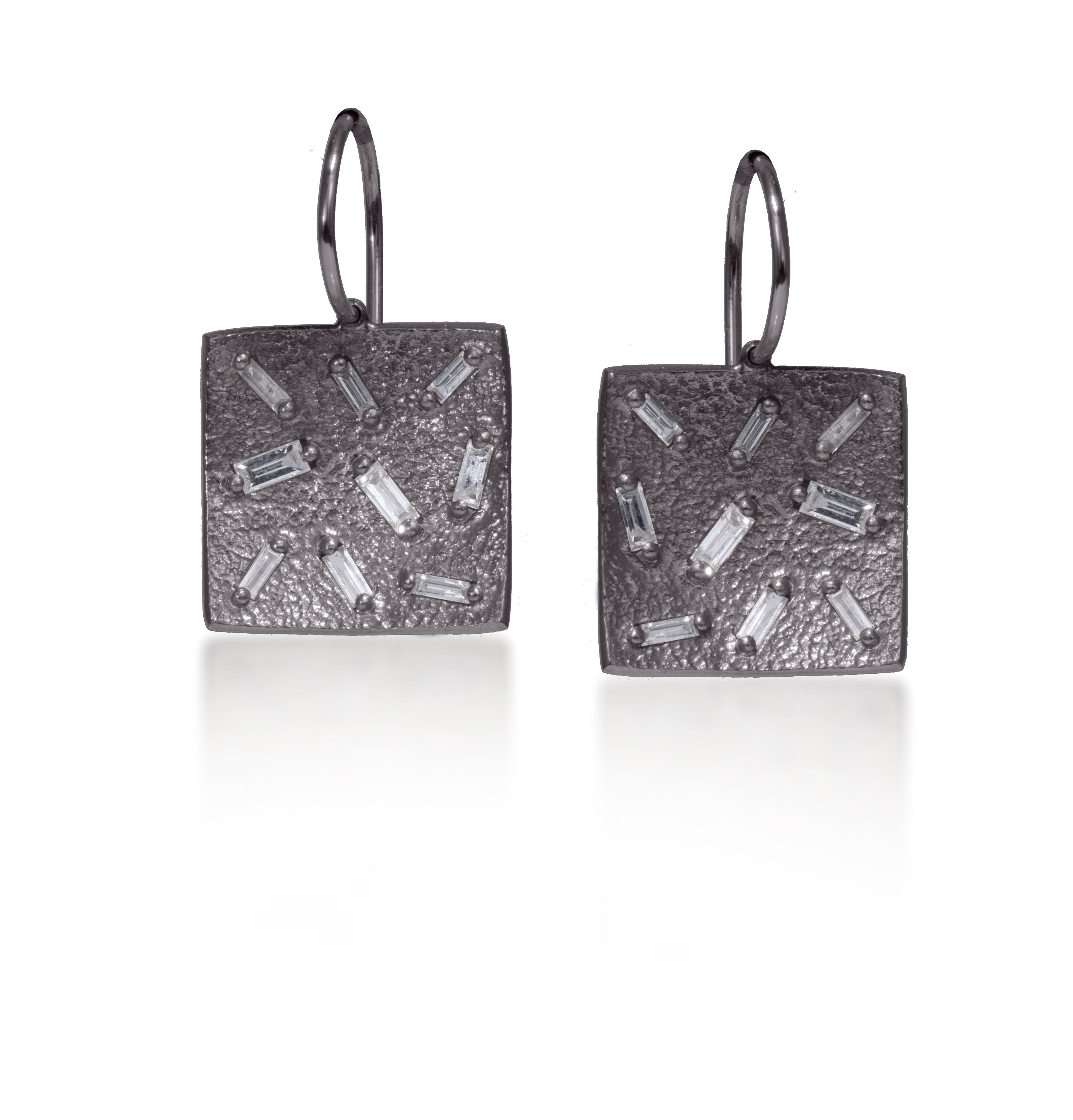 This simple yet elegant drop earring is perfect for everyday. Offered in three richly textured color ways, oxidized sterling, 18k gold, palladium. Each earring set with 9 white diamond baguettes. 0.5 tcw.