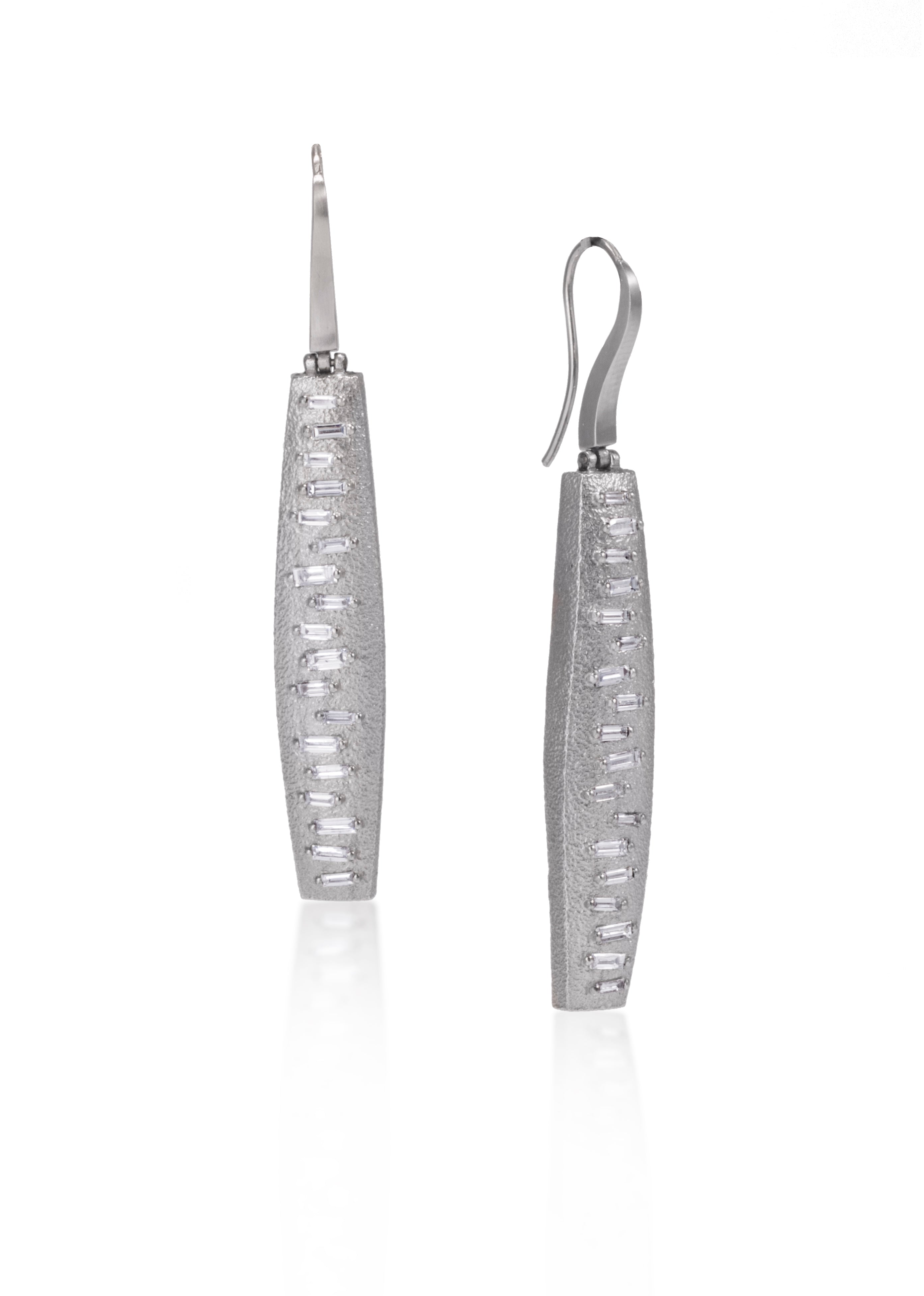 This earring features a hinged earwire, with a graceful, curved and tapered form. The playful irregularity of the baguette angles catch the light in dynamic ways. Design is offered in four richly textured colorways, oxidized sterling, oxidized sterling/18k gold, 18k gold and palladium. Each earring set with 36 total white diamond baguettes. 1.1104 tcw.
