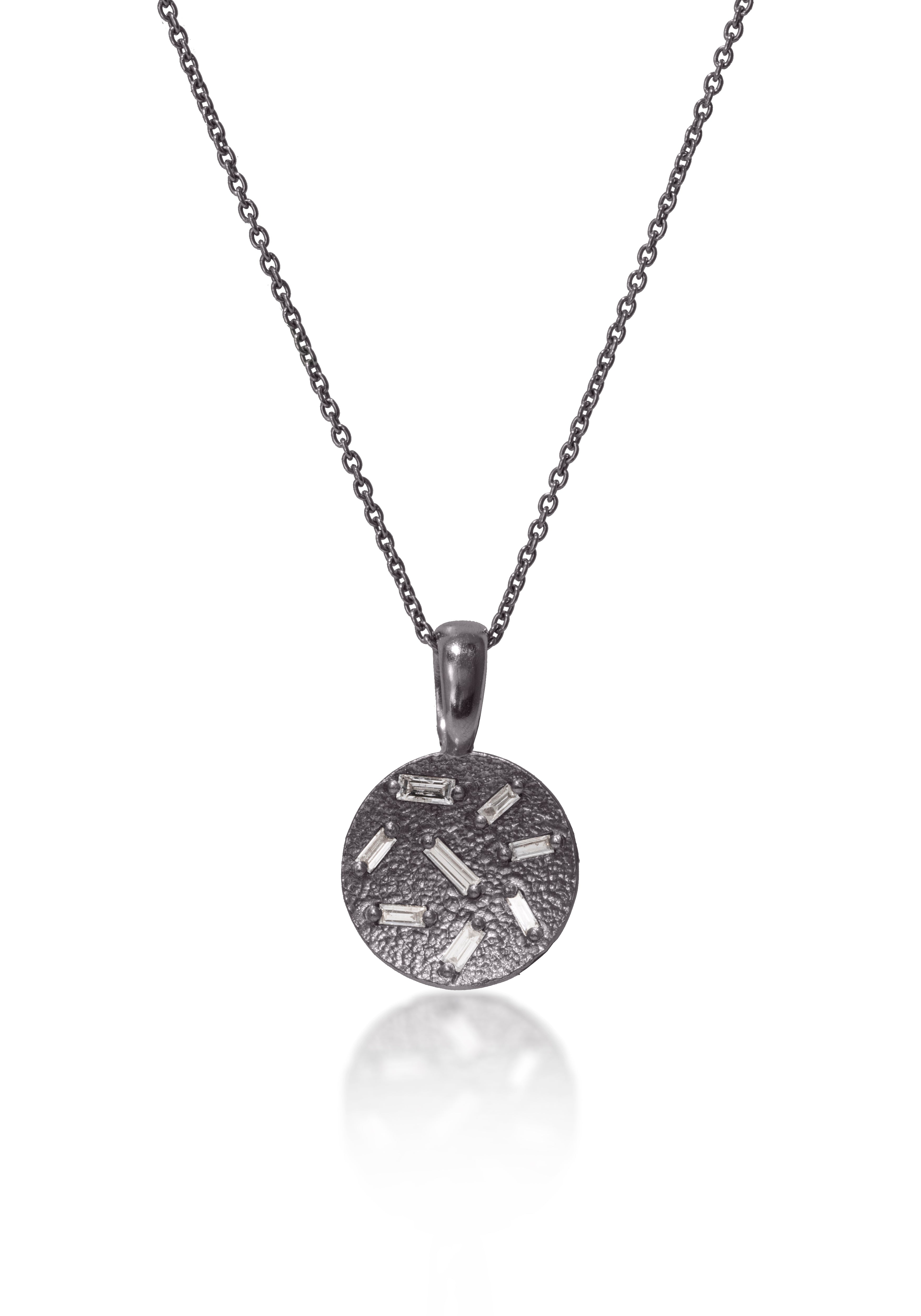 This stunning, small circular pendant is set with 8 white diamond baguettes. Richly textured to shimmer in the light, this piece is available in three color ways, oxidized silver, 18k gold and palladium.  0.227 tcw.