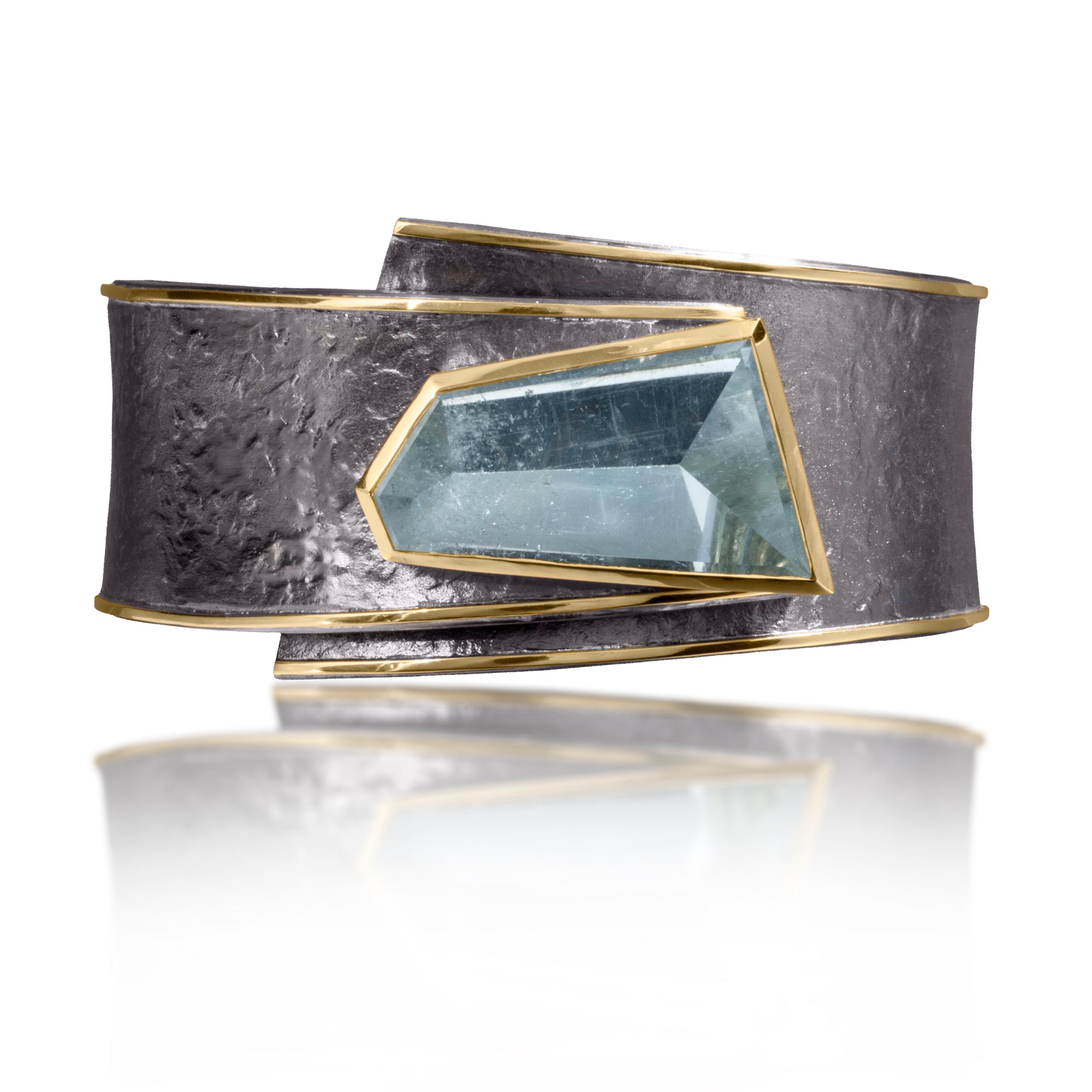 This one-of-a-kind Cyclone Cuff in 18k gold and oxidized silver isbezel set with a dramatic, mirror-cut Aquamarine, A hinge on the back side of this tapered cuff allows it to fully open, making it incredibly easy to put on and off with one hand. Wide, wrap-around style cuff, hand fabricated, spring steel hinge, hammer textured.