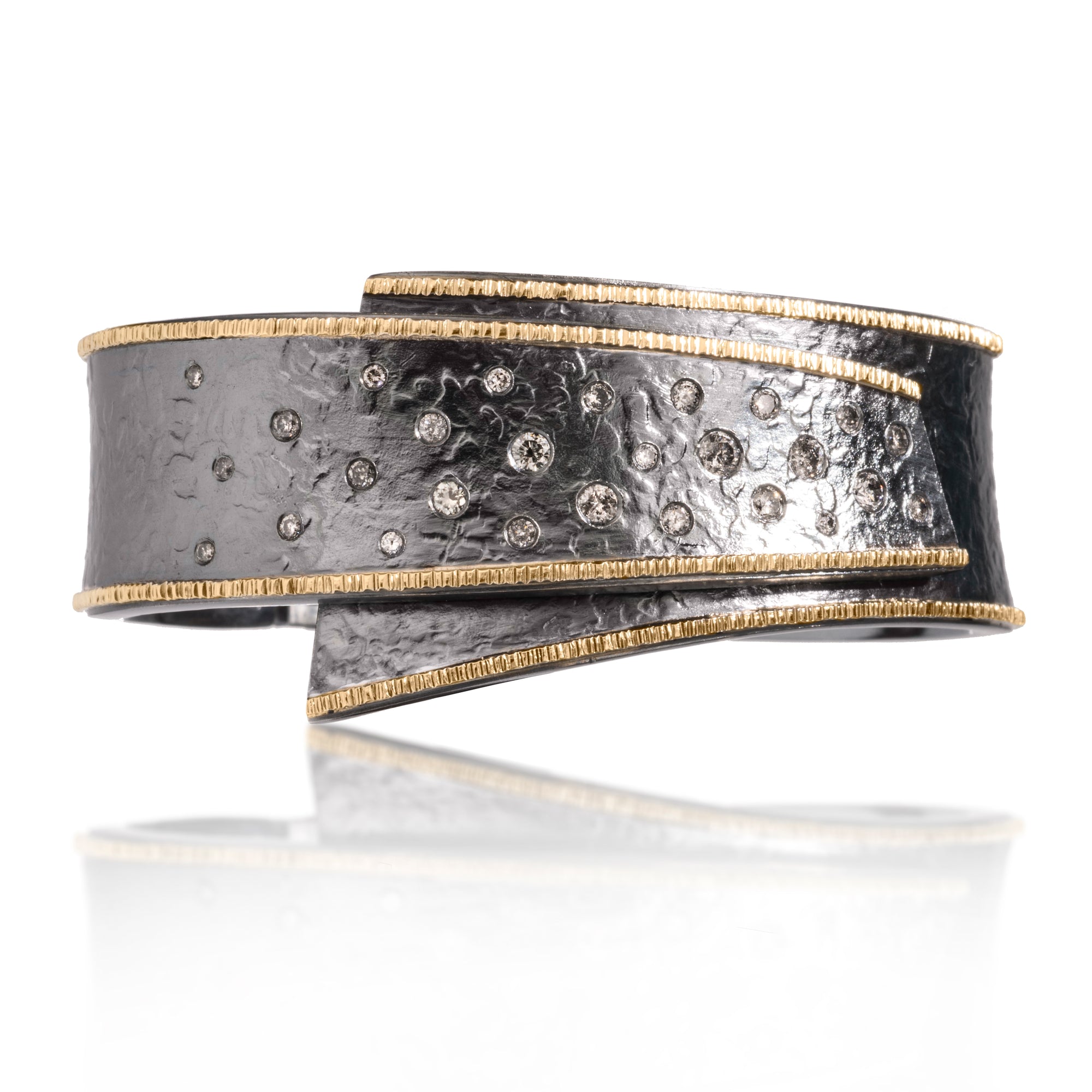 This narrow width Cyclone Cuff is created in 18k gold and oxidized silver featuring a sparkling spray of flush set, assorted white or gray diamonds. A hinge on the back side of this tapered cuff allows it to fully open, making it incredibly easy to put on and off with one hand. Hand fabricated, spring steel hinge, hammer textured. Diamonds 1.00 tcw. Bracelet can be ordered in five different sizes for just the right fit.