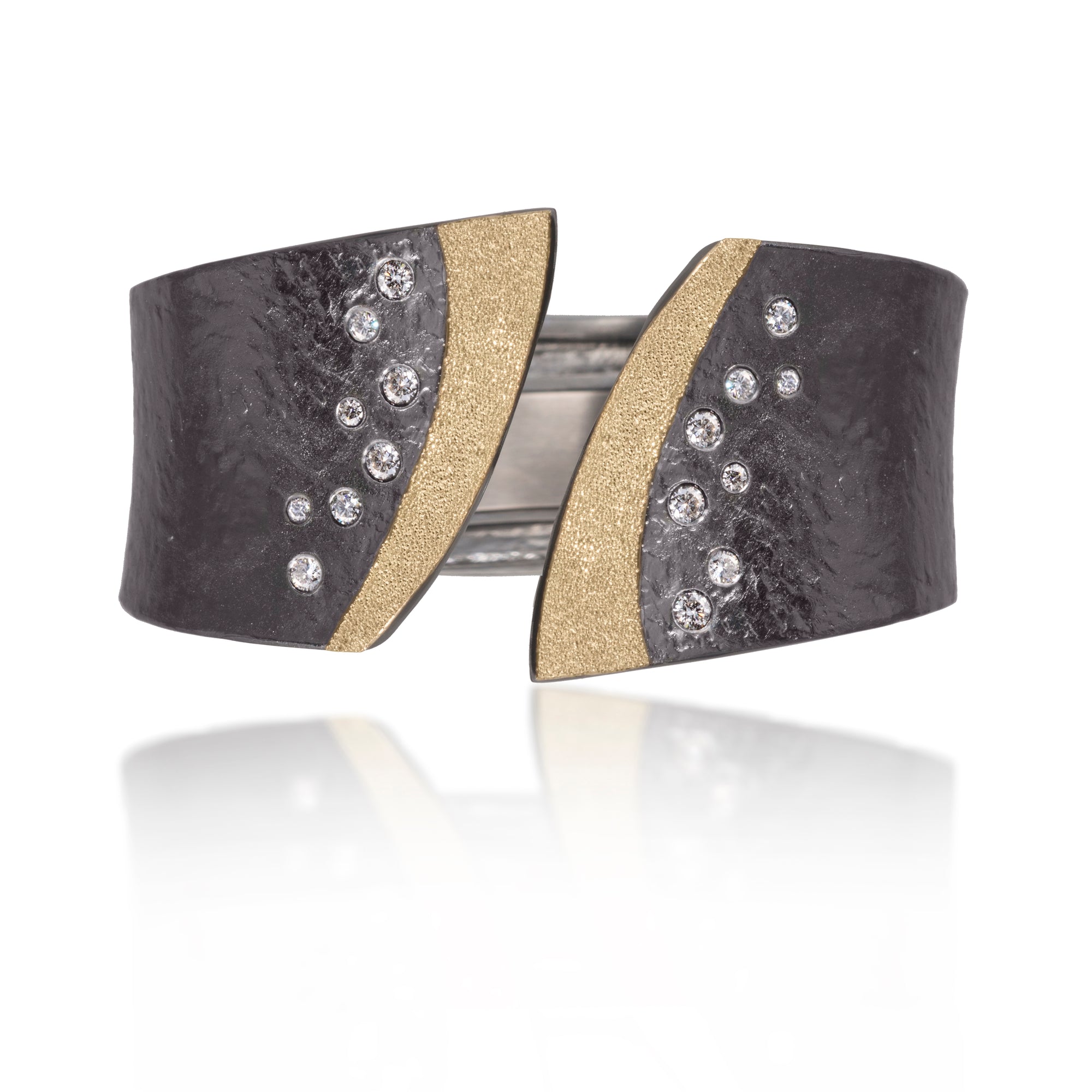 This striking Cyclone Cuff in 18k gold and oxidized sterling silver is flush set with assorted diamonds. A hinge on the back side of this tapered cuff allows it to fully open, making it incredibly easy to put on and off with one hand. Symmetric bypass style, hand fabricated, with a spring steel hinge and hammered textured. Available with white or gray diamonds. As shown, 0.59 tcw.