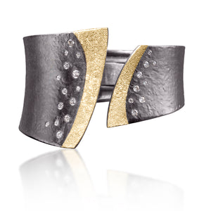 This striking Cyclone Cuff in 18k gold and oxidized sterling silver is flush set with assorted diamonds. A hinge on the back side of this tapered cuff allows it to fully open, making it incredibly easy to put on and off with one hand.  Symmetric or asymmetric, bypass style, hand fabricated, with a spring steel hinge and hammered textured. Available with white or gray diamonds.  As shown 0.78 tcw.