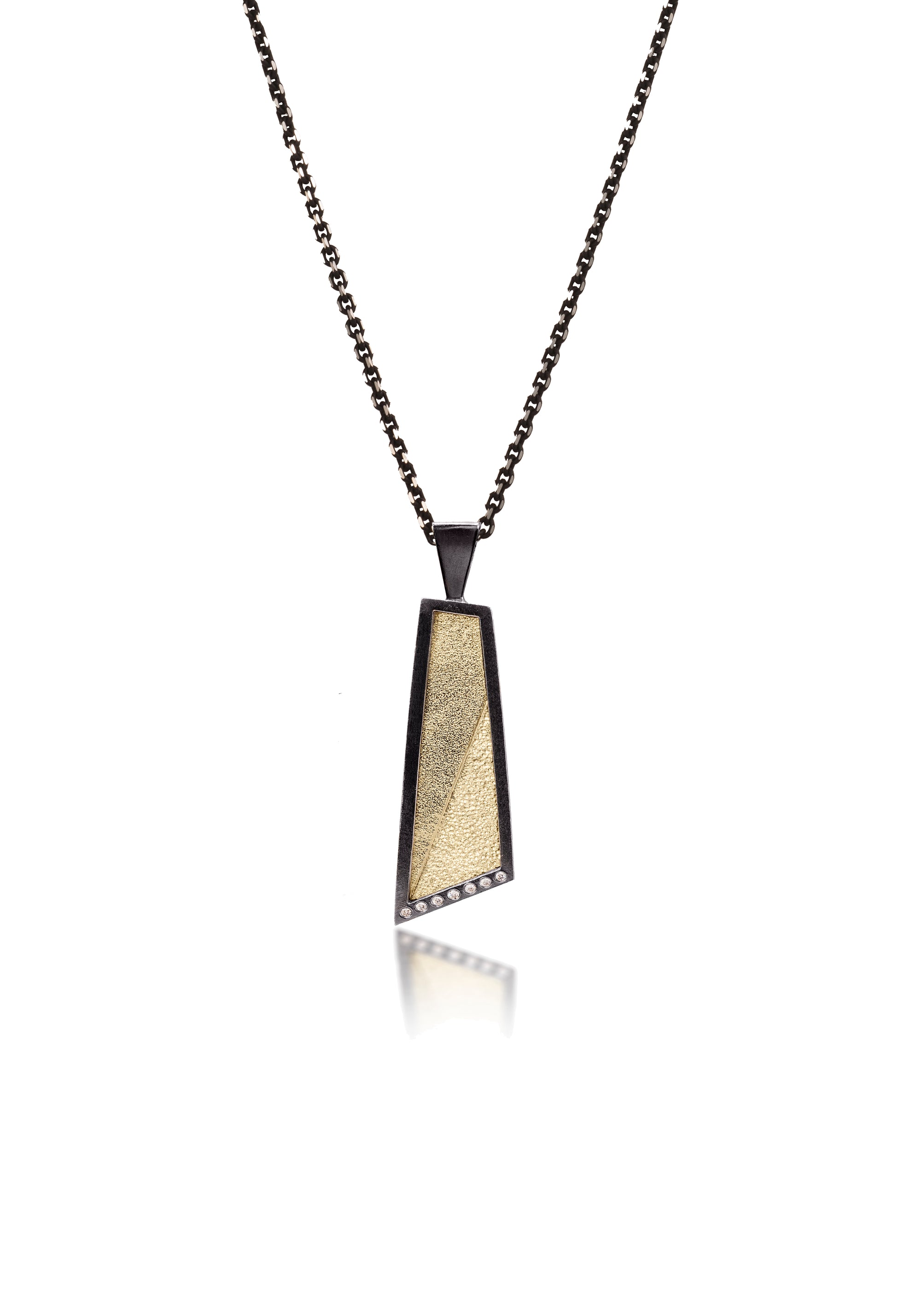 This oxidized sterling silver and richly textured 18k bimetal pendant is flush set with ideal cut white diamonds.  Accent facet glitters with the texture of diamond facets, individually scored and textured.  Elongated shape in medium length, available with or without diamond cut chain fringe. 0.0483 tcw 