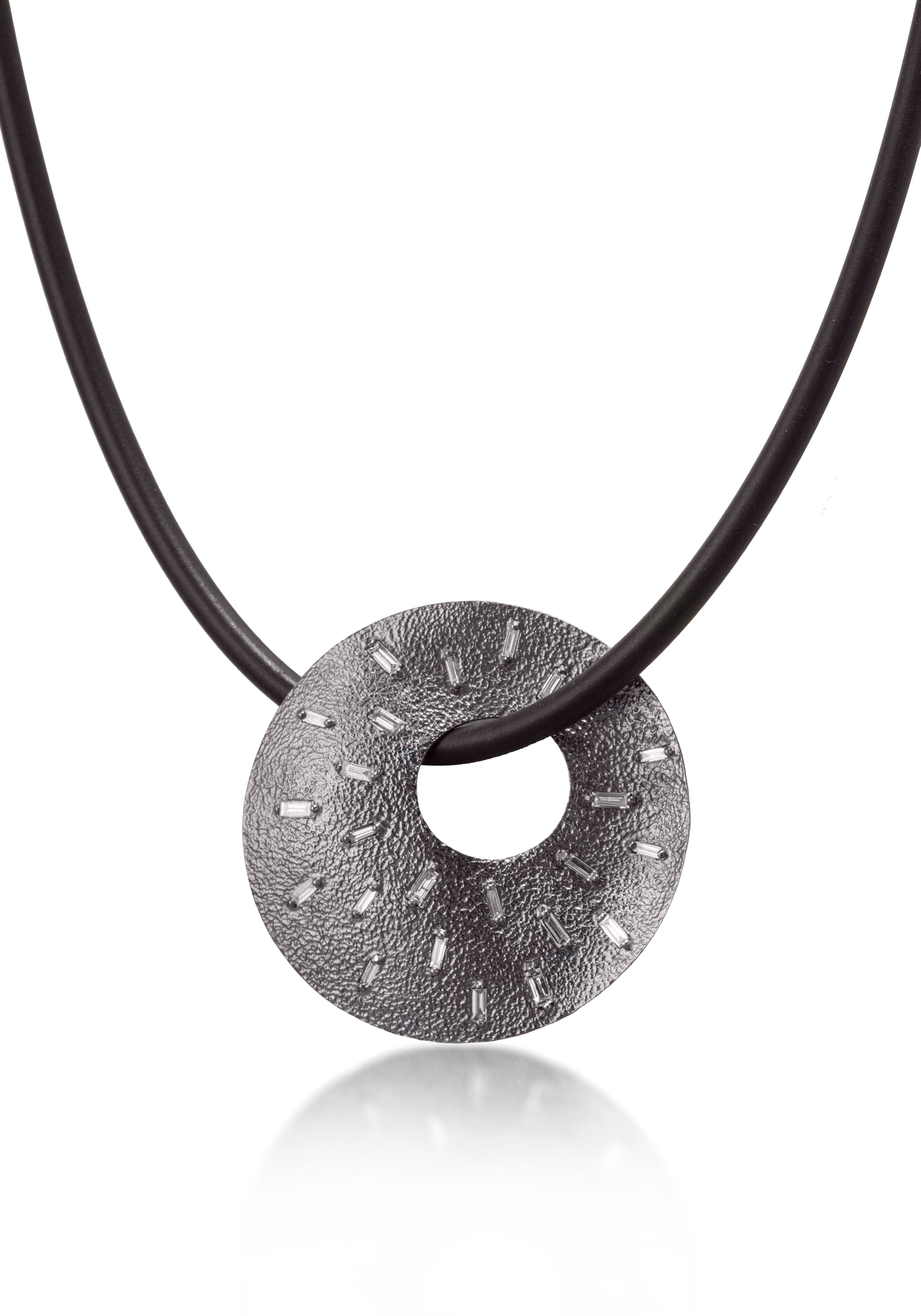 This unique radial pendant makes elegant use of space and line.  Featuring 26 white diamond baguettes and richly textured oxidized silver, the necklace comes to life with the slightest bit of light.  0.778 tcw