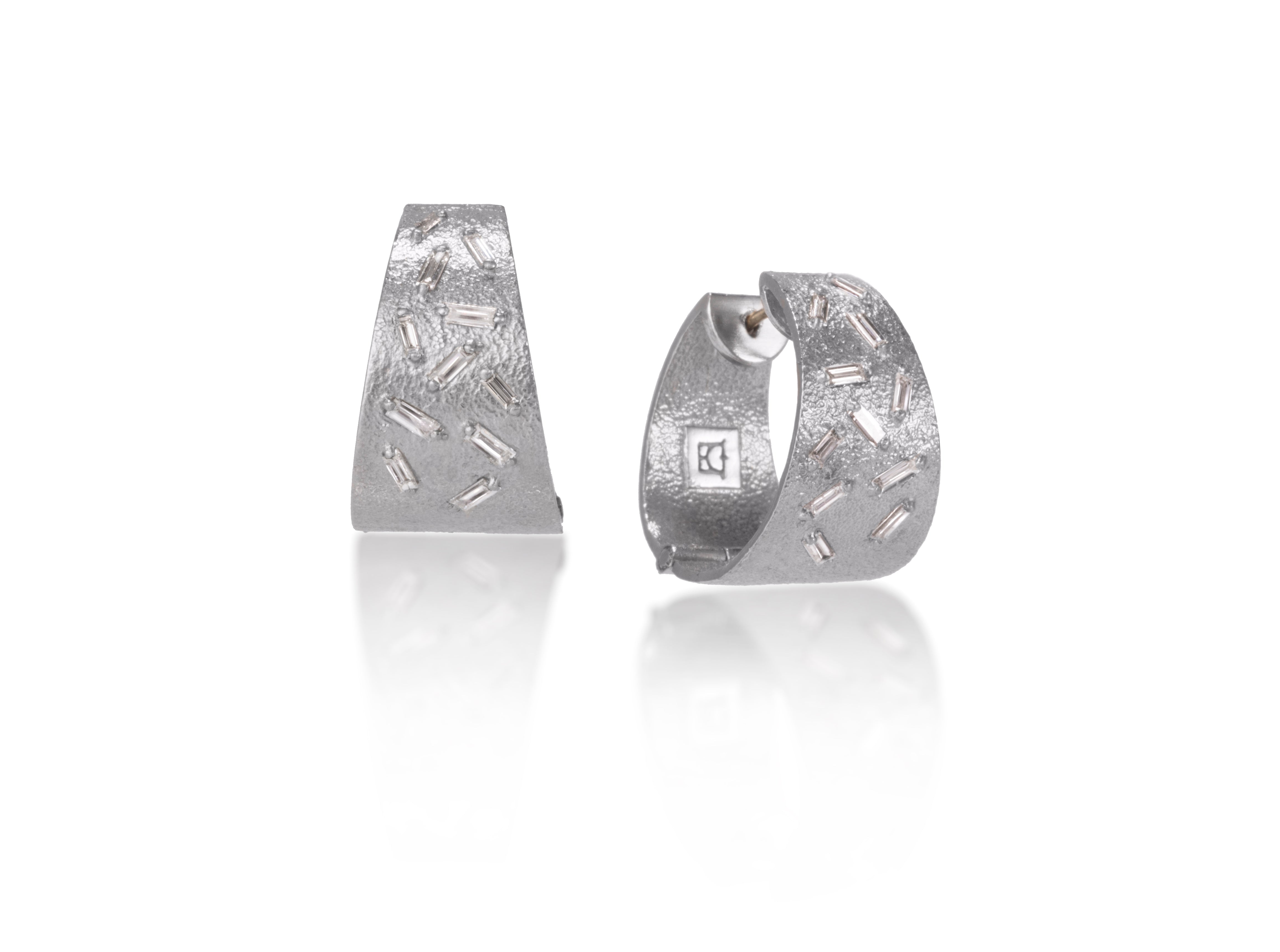 These all in one huggie style earrings are each set with 11 white diamond baguettes. This smaller huggie option earring is available in three richly textured color ways, oxidized sterling, 18k gold and palladium.  .696 tcw.  