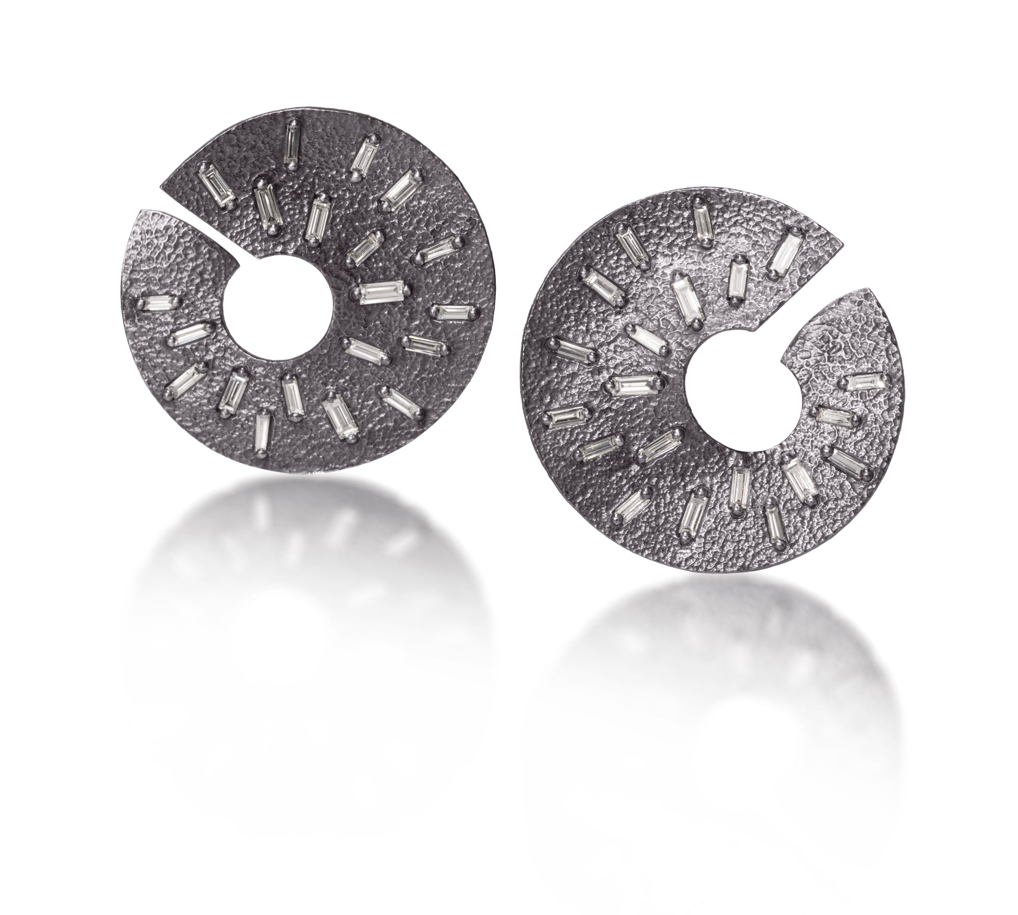 The larger of two radiant styled earrings, this one created in oxidized sterling, each set with 22 white diamond baguettes. Richly textured and designed three dimensionally to wrap around from the front to behind the ear. 1.316 tcw.