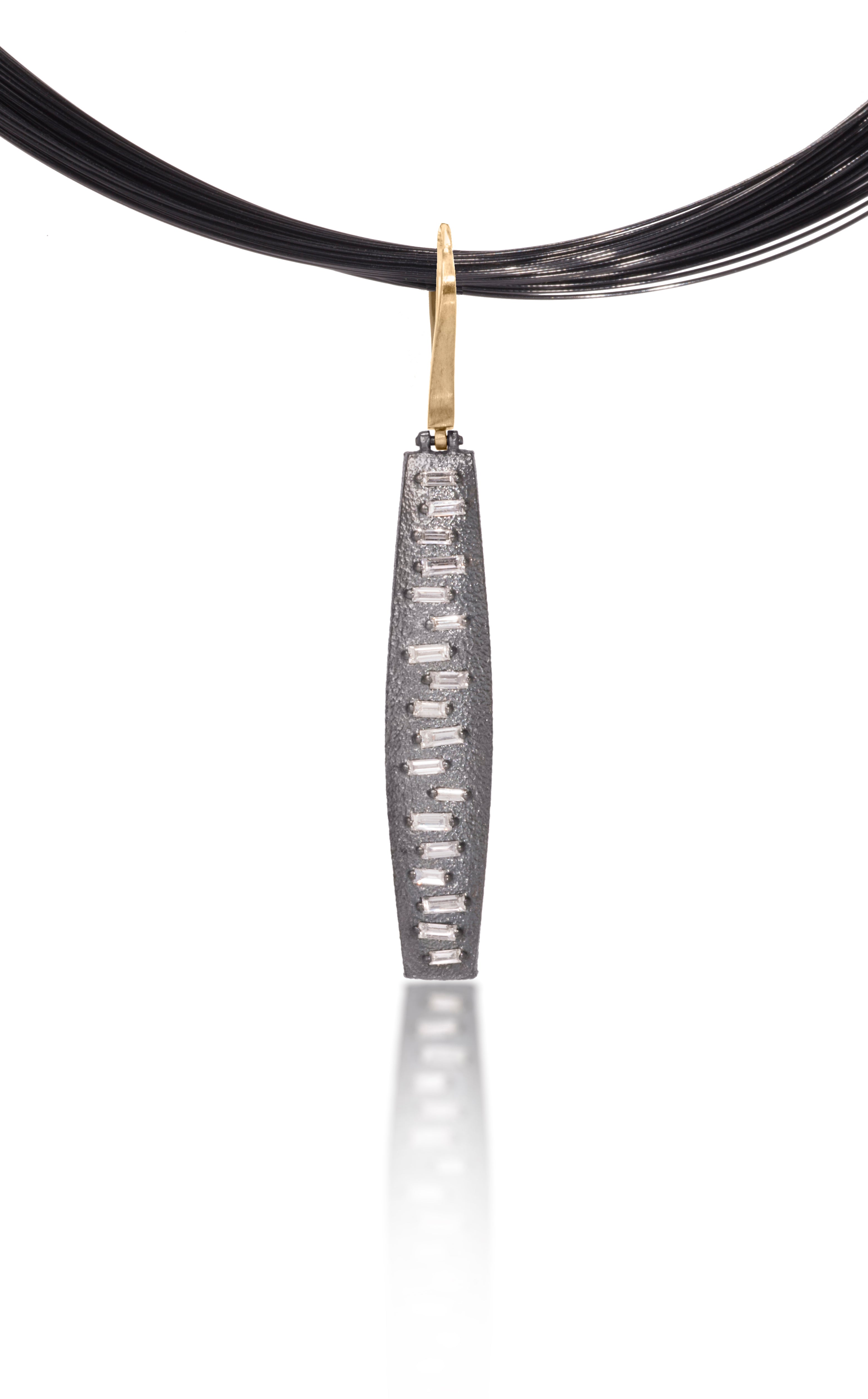 This hinged pendant features a graceful, curved and tapered form. The playful irregularity of the baguette angles catch the light in dynamic ways when worn. Design is offered in four richly textured color ways, oxidized sterling, oxidized sterling/18k gold, 18k gold and palladium. 0.555 tcw.