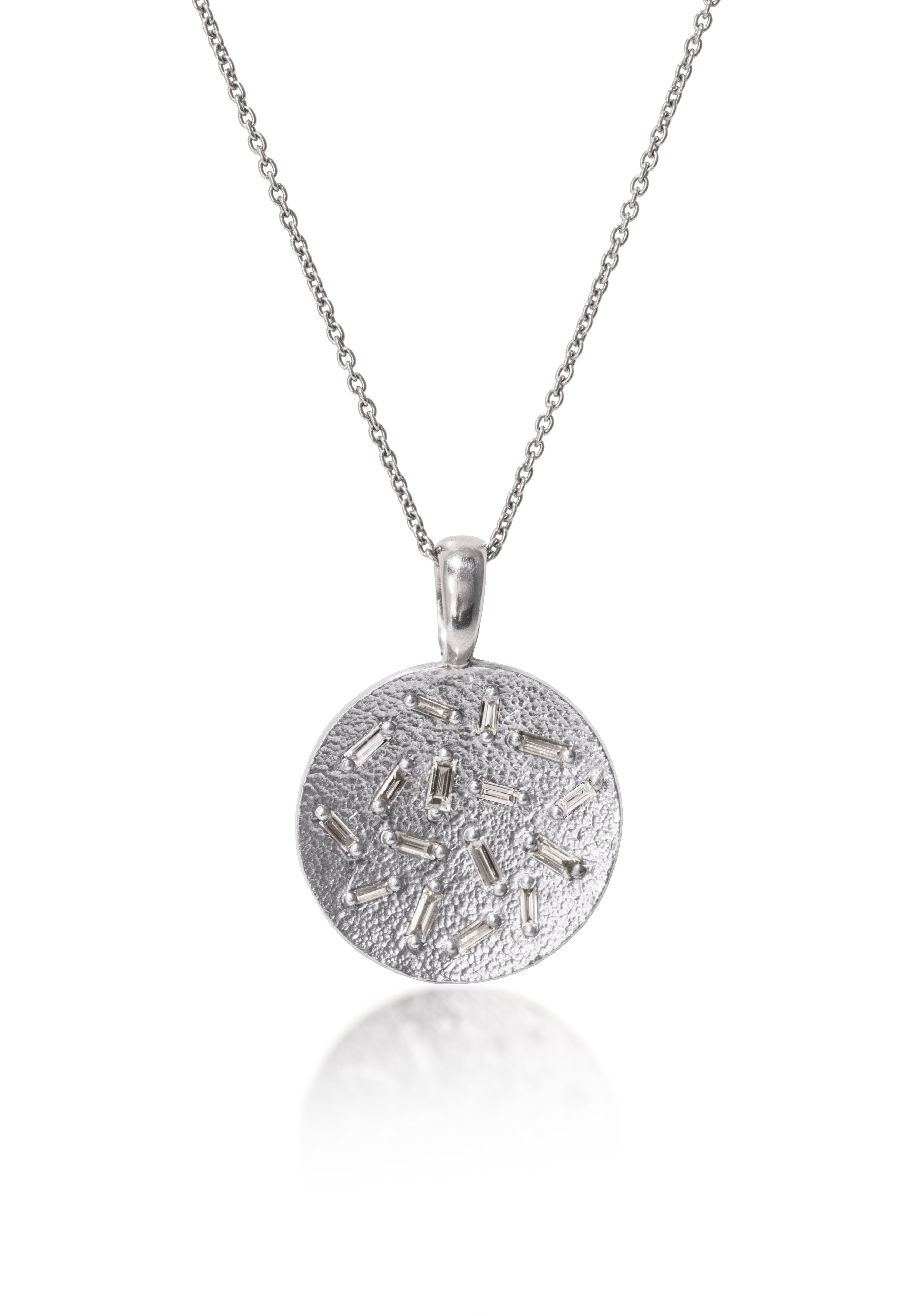 This radiant, medium size circular pendant is set with 16 white diamond baguettes. Richly textured to shimmer in the light, this piece is available in three color ways, oxidized silver, 18k gold and palladium.  0.435 tcw.