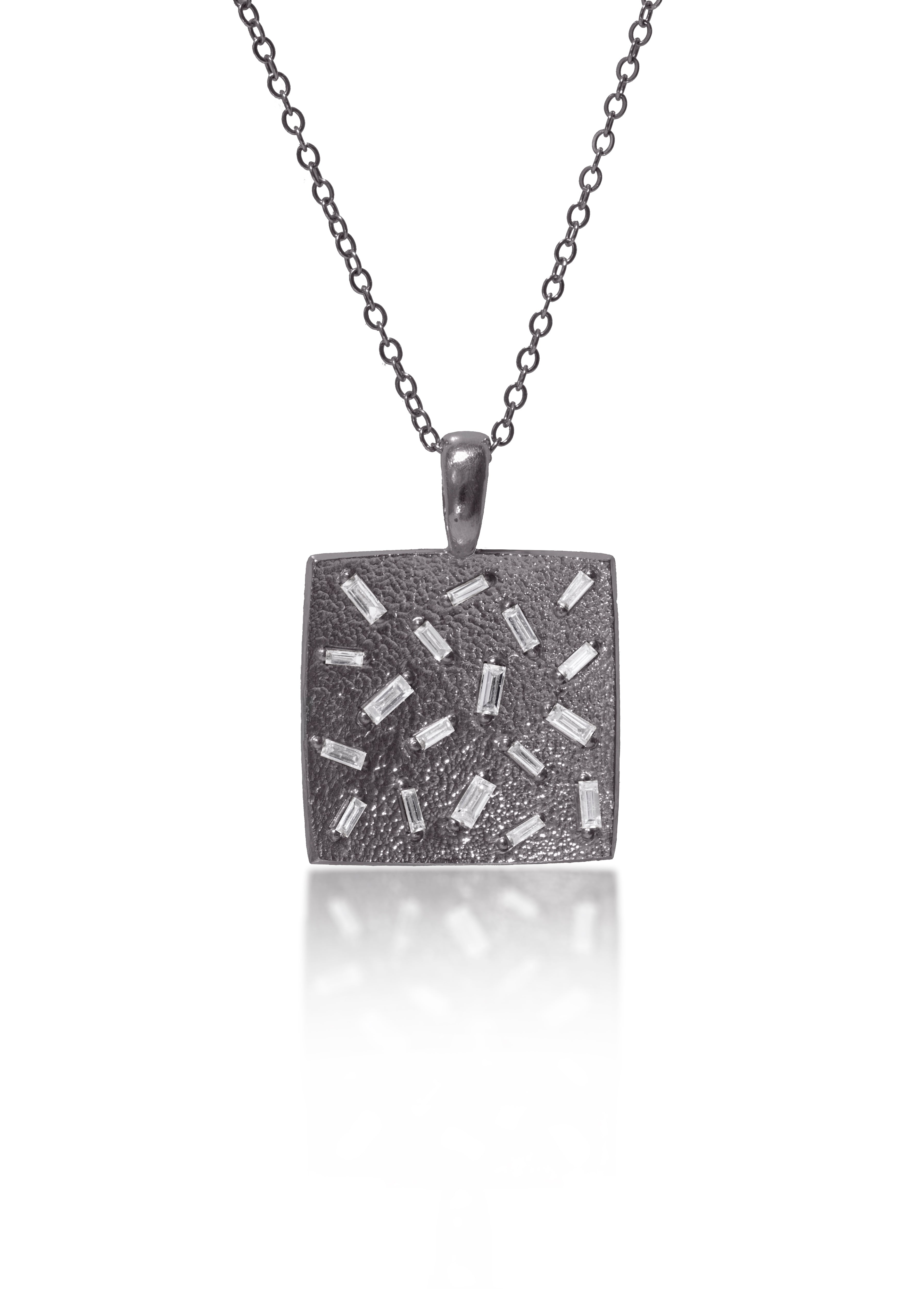 This medium size square pendant is set with 18 white diamond baguettes. Richly textured to shimmer in the light, this piece is available in three color ways, oxidized silver, 18k gold and palladium.  0.486 tcw.