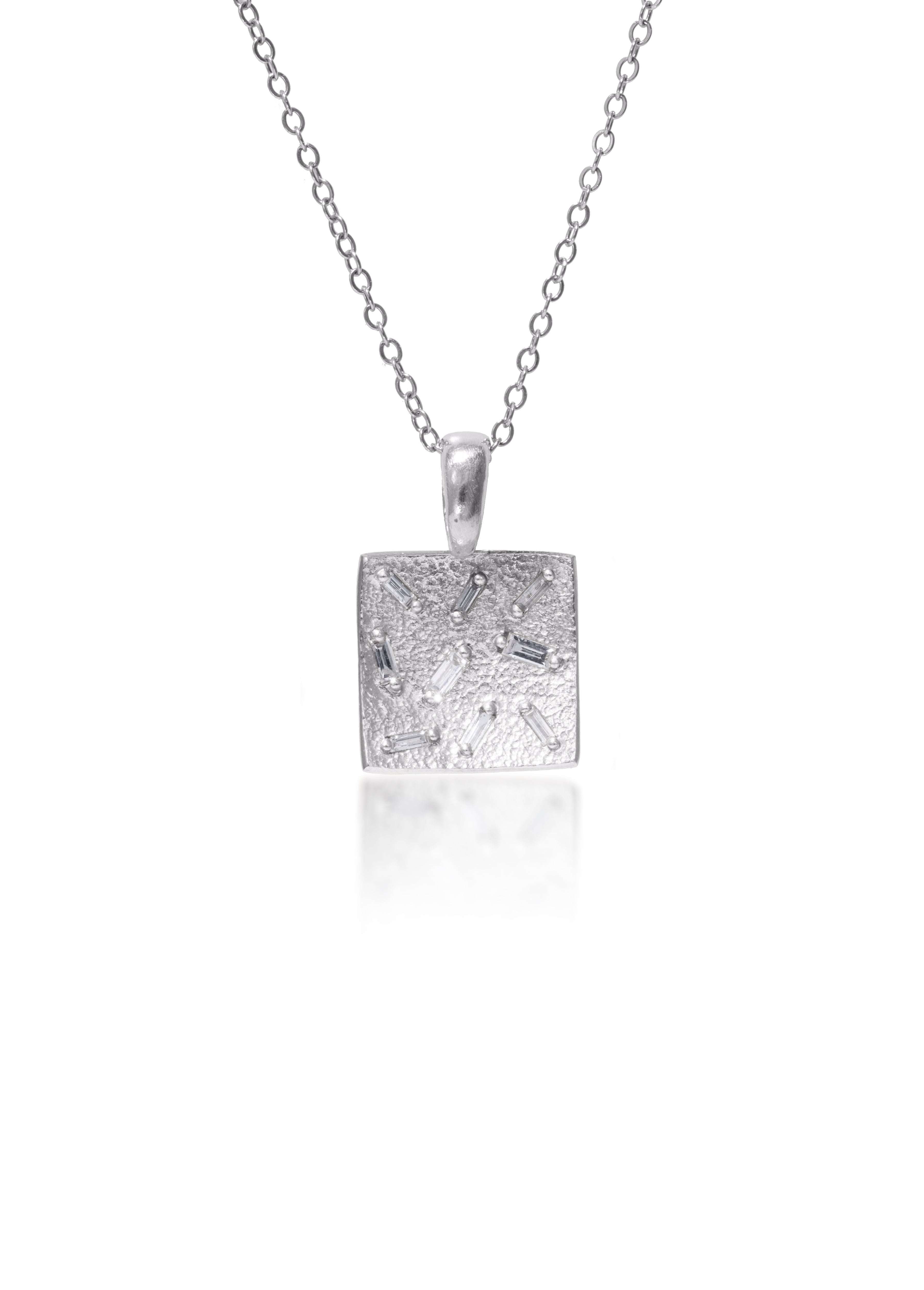 This stunning, small square pendant is set with 9 white diamond baguettes. Richly textured to shimmer in the light, this piece is available in three color ways, oxidized silver, 18k gold and palladium (pictured).  0.245 tcw.