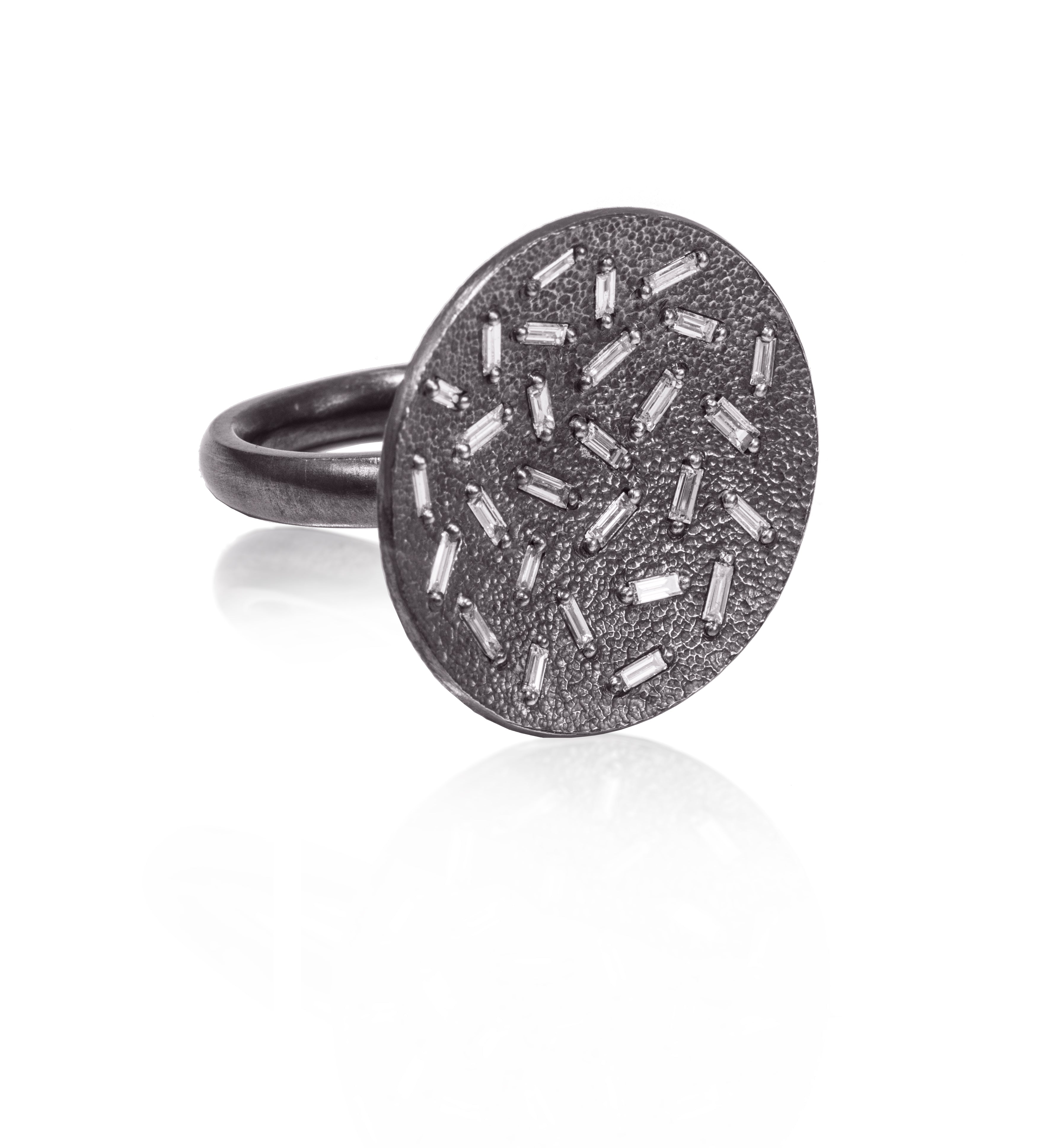 This large circular pendant ring in oxidized silver is set with 28 white diamond baguettes.  The random angles of the baguettes catch the light in exciting ways when worn. 0.796 tcw.